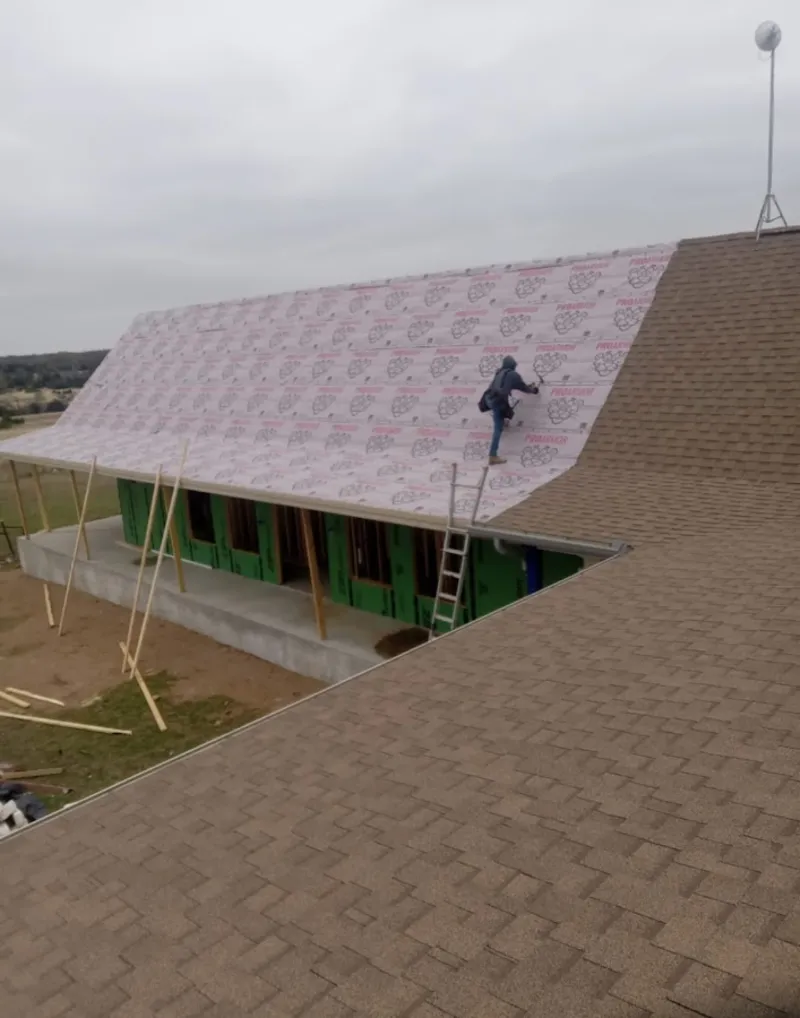 Worker preparing underlayment for a metal roof installation in Plover